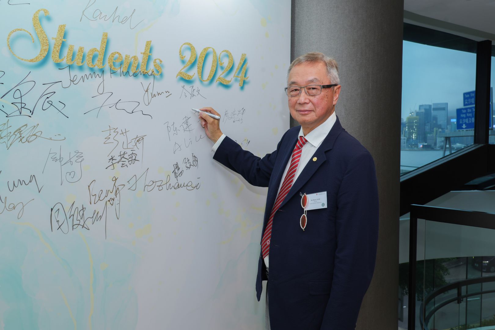 岑展文学长在2024毕业同学晚宴的背景板上签名的照片。