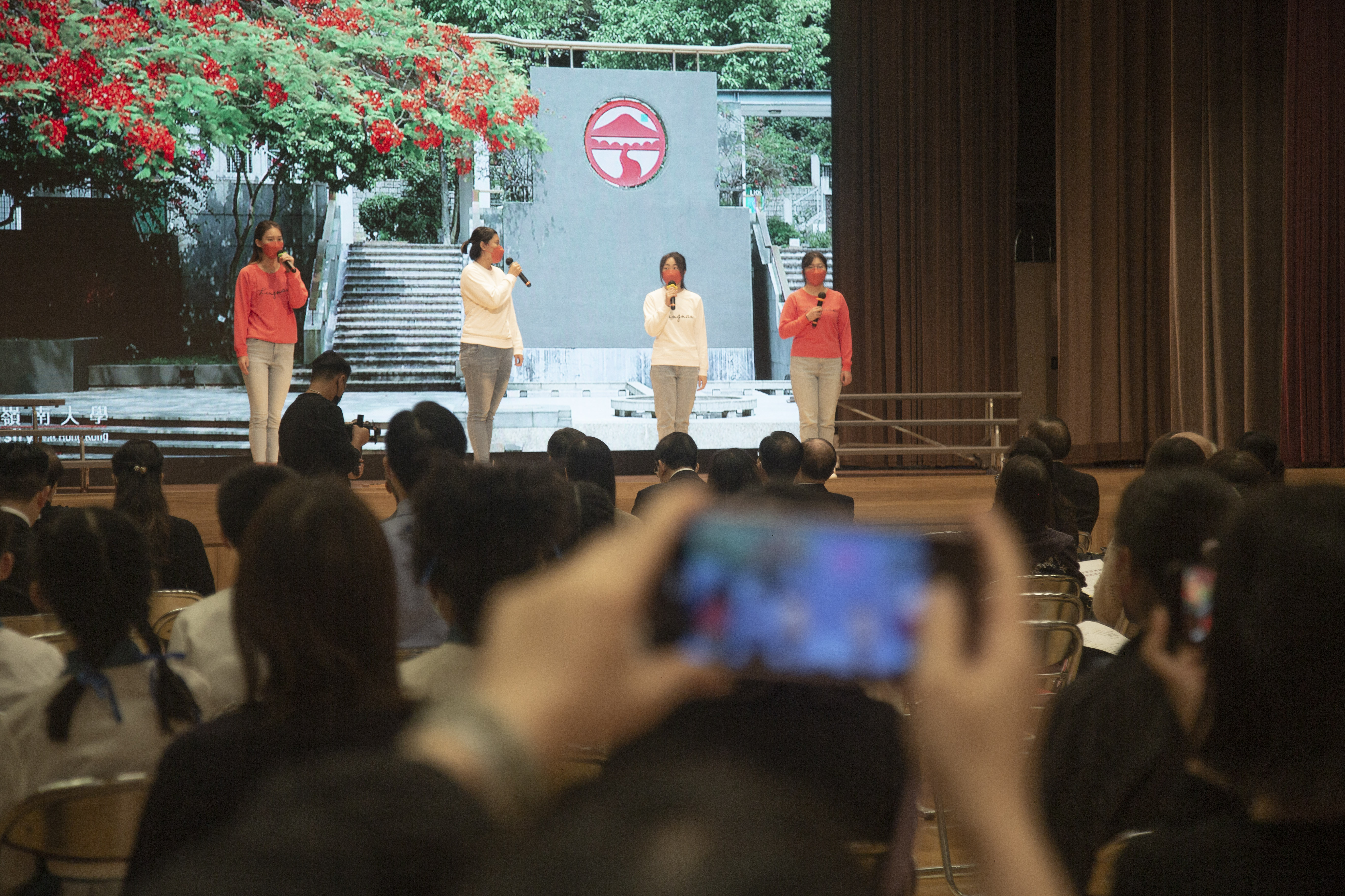遠距離拍攝4位嶺大學生在台上誦讀