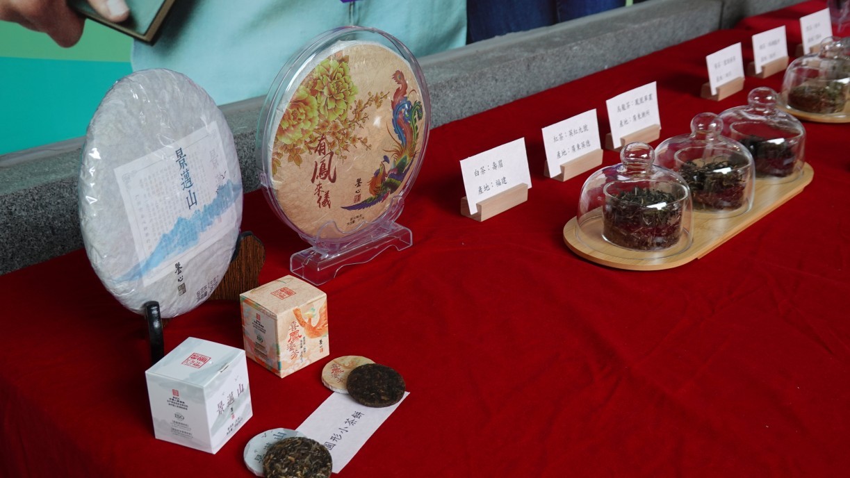 A tea display area outside the venue shows different varieties and packaging.