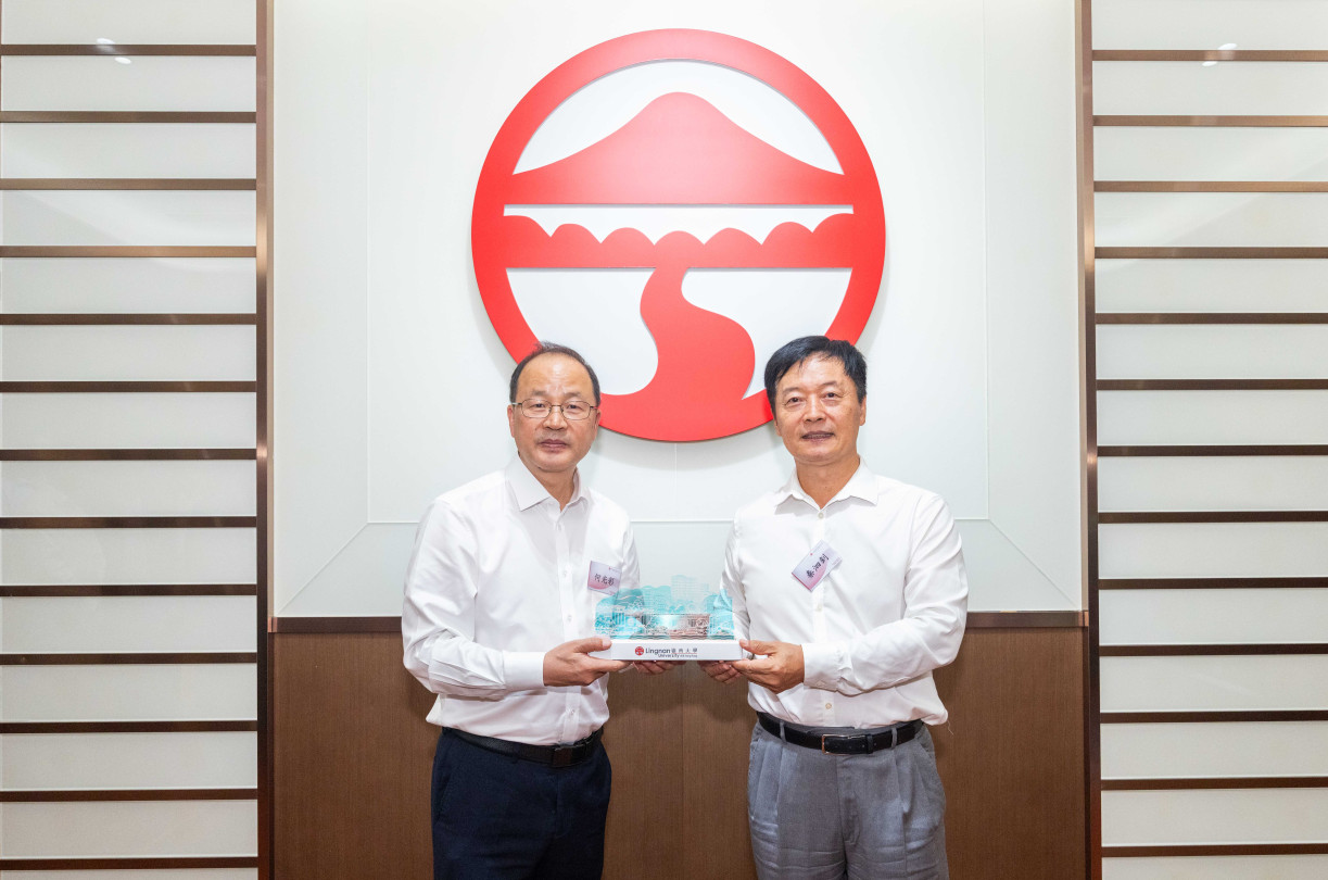 Prof S. Joe Qin, President and Wai Kee Kau Chair Professor of Data Science at Lingnan University (right), presents a souvenir to Mr He Guangcai, Secretary of the CPC Peking University Committee (left).