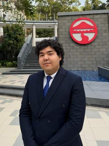 Professional‑looking Kazakhstan student in front of Lingnan University emblem on campus in Hong Kong