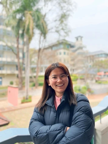 Candid photo of Myanmar student smiling with Lingnan University campus greenery behind