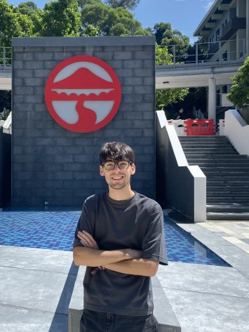 Spanish student smiling in front of Lingnan University emblem on Hong Kong campus