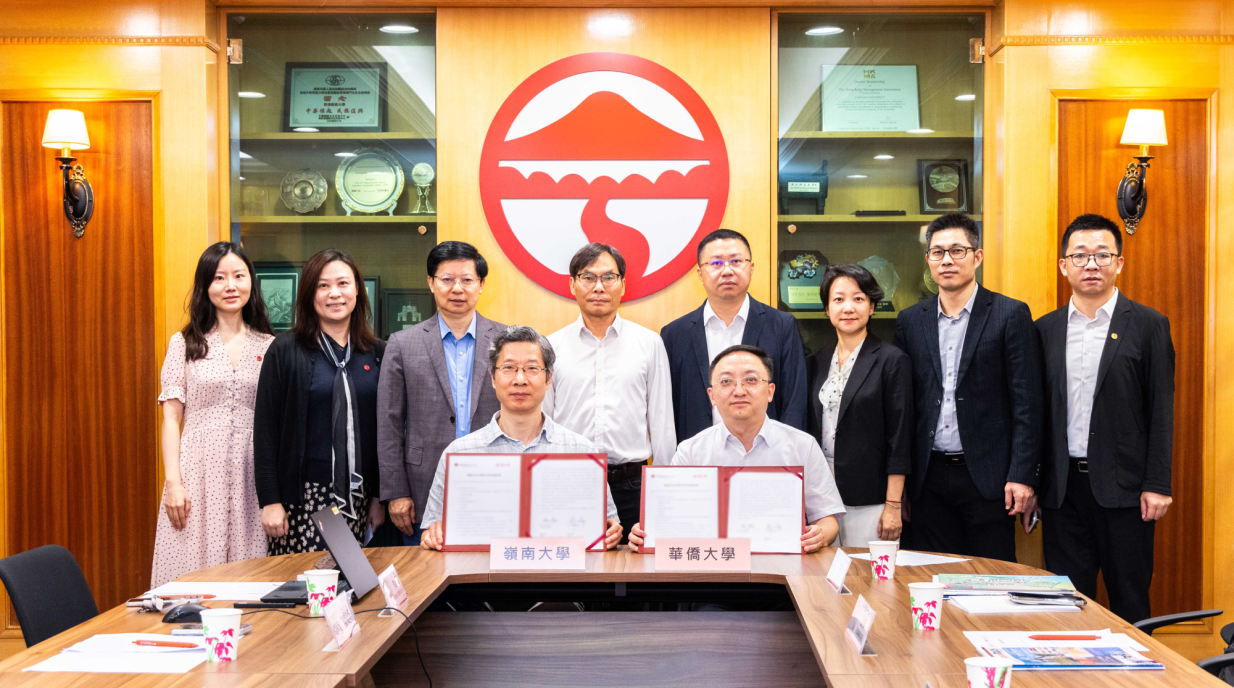 2026年7月21日岭南大学与华侨大学合作备忘录签署仪式,两校代表于桌前签署,随行人员在后方合影