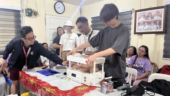  Student researchers demonstrating the portable Bloom baby incubator prototype to local community health workers during a field testing session in the Philippines.