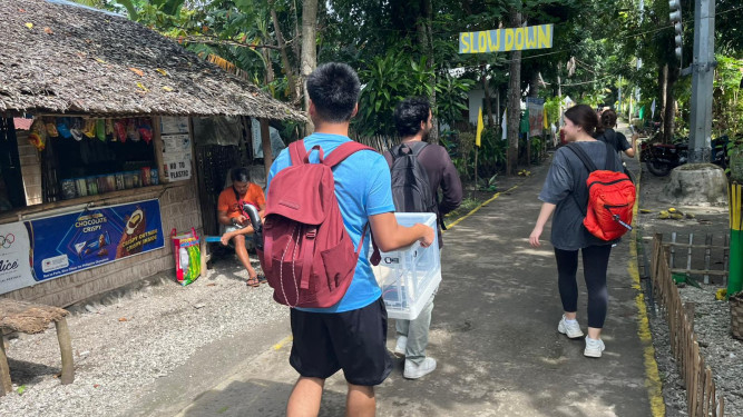  Student researcher team carrying a baby incubator prototype along a village path in the Philippines.