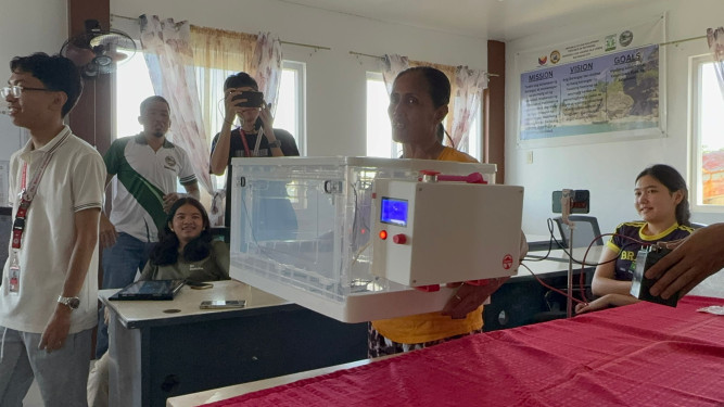  A local woman holding the baby incubator prototype during a field testing session.