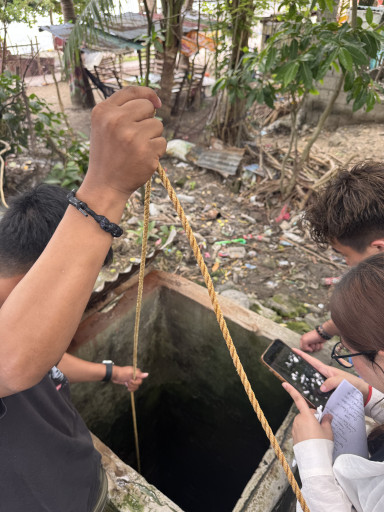  Student researchers extracting water samples from a well for analysis during field research.