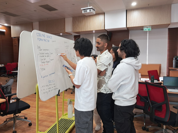  Students brainstorming cooling device design concepts on a whiteboard during a workshop.