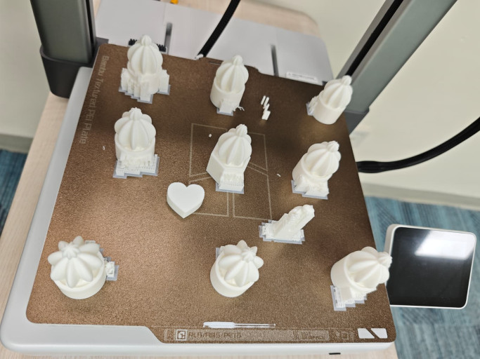 Freshly 3D-printed white cactus miniatures on a printer build plate.