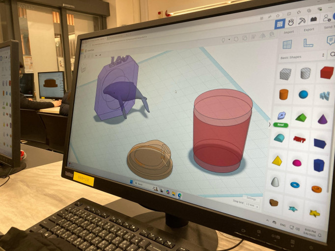 Computer monitor displaying custom 3D models in Tinkercad during a lab session.