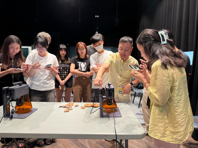  Students watching a live LaserPecker laser engraving demonstration during a workshop.