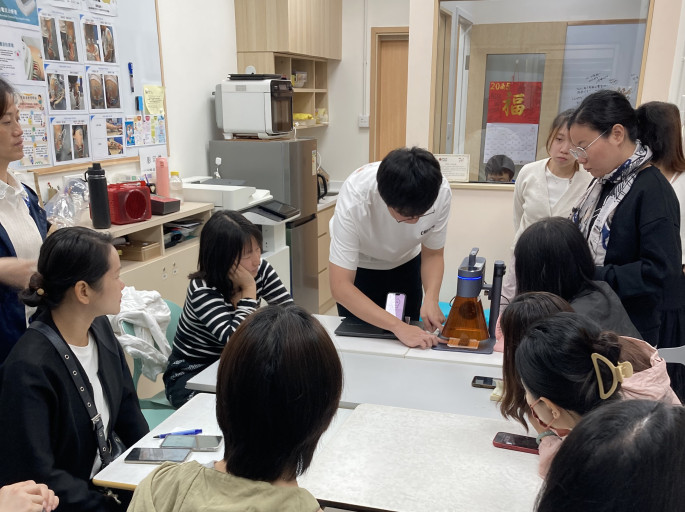 Workshop participants watching a laser engraving demonstration.