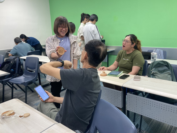  Workshop participant happily displaying her custom laser-engraved wooden coaster.