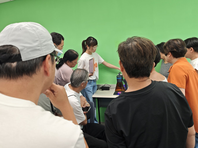  Instructor demonstrating laser engraving equipment to a group during a workshop.
