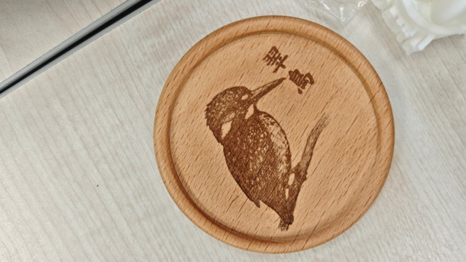 Laser-engraved wooden coaster with a kingfisher illustration and Chinese text.