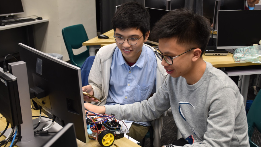 Students collaborating on an Arduino robotic car project in a computer lab.
