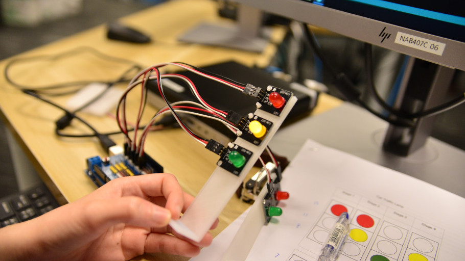  Arduino-controlled LED traffic light prototype being tested next to a sequence worksheet.