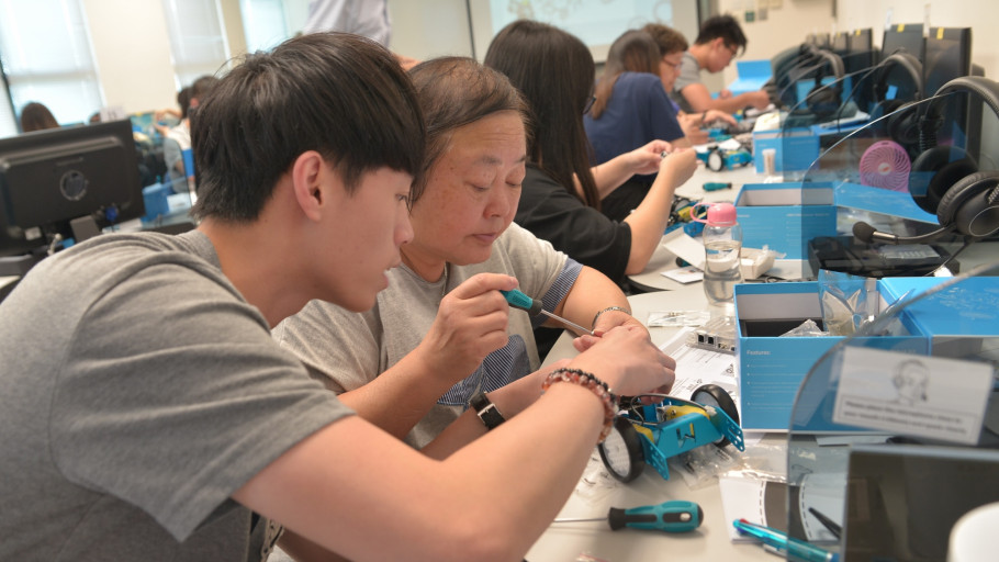  Participant and mentor assembling an educational robotic car kit in a computer lab.