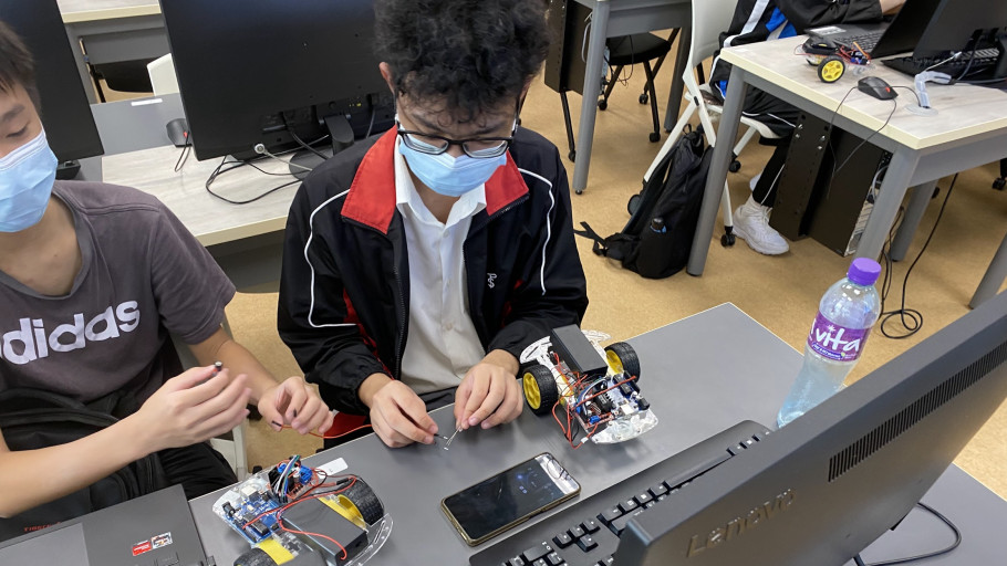 Students wiring a robotic car kit in a computer lab classroom.