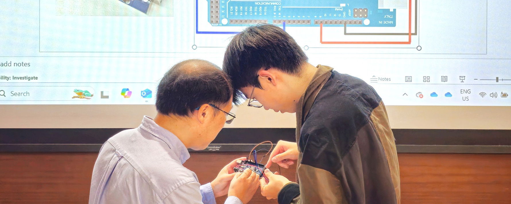 Instructor helping a student wire an Arduino board during a technical workshop.