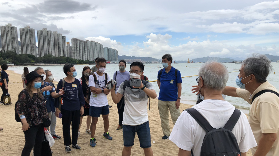  Instructor demonstrating drone remote control operation to participants on a beach.