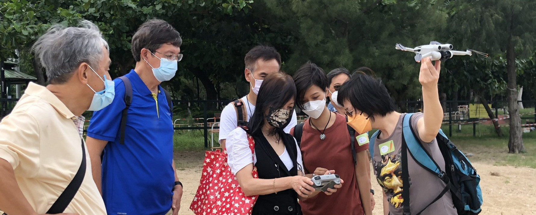 Outdoor community workshop participants observing a drone flight demonstration.