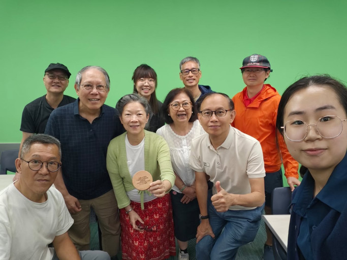  Group photo of a HIT Part-time Project Assistant and workshop participants in front of a green screen.