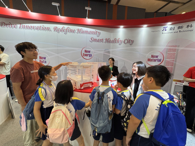 Project Assistants presenting the baby incubator to visiting school children at an innovation exhibition.