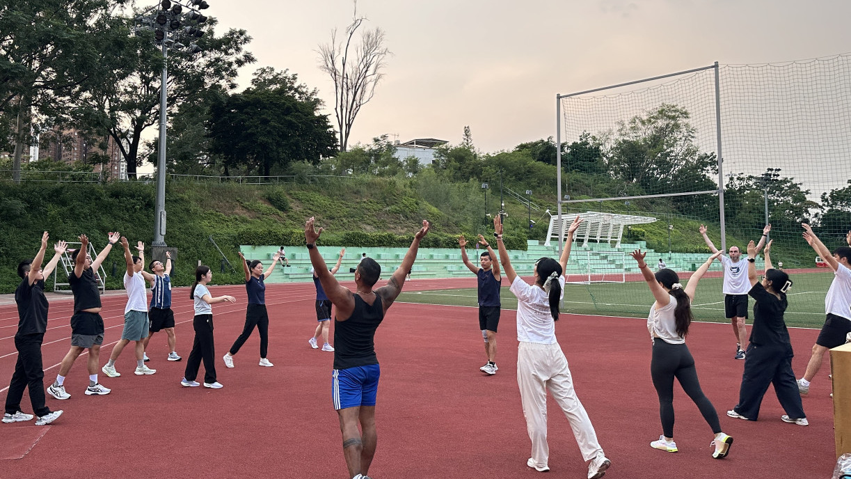 Coach Ngai leads a warm-up session before the running begins.